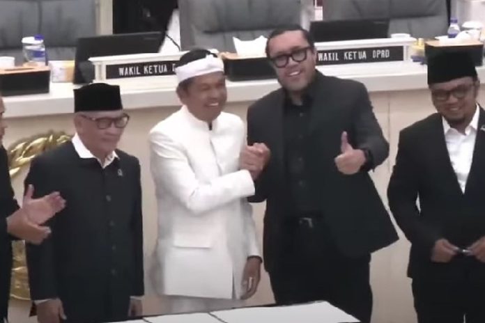 Suasana hangat dan penuh keakraban tampak dalam Rapat Paripurna DPRD Jawa Barat di Bandung, Kamis (22/5/2025). Gubernur Jawa Barat Dedi Mulyadi terlihat berdiri berdampingan dengan Wakil Ketua DPRD Jabar dari Fraksi PDI Perjuangan, Ono Surono. Keduanya tersenyum lebar sambil bersalaman.(Tangkapan layar KompasTV) Suasana hangat dan penuh keakraban tampak dalam Rapat Paripurna DPRD Jawa Barat di Bandung, Kamis (22/5/2025). Gubernur Jawa Barat Dedi Mulyadi terlihat berdiri berdampingan dengan Wakil Ketua DPRD Jabar dari Fraksi PDI Perjuangan, Ono Surono. Keduanya tersenyum lebar sambil bersalaman.(Tangkapan layar KompasTV)